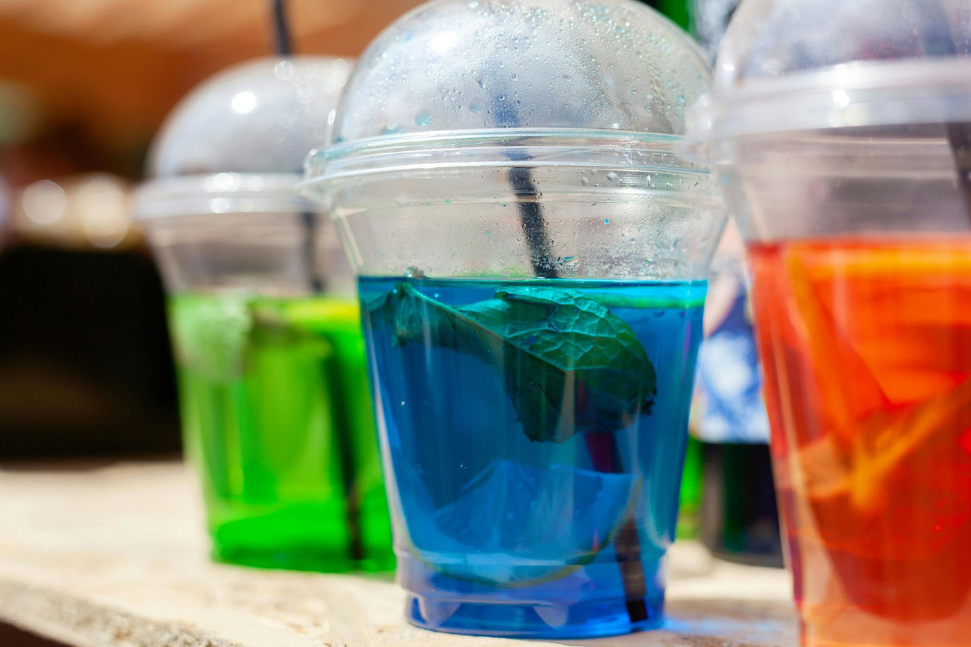 Brightly coloured beverages in plastic cups with mint leaves, showcasing natural colours and clean label appeal.